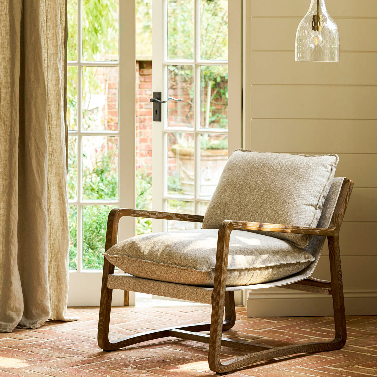 Chair with cushions in a room with large windows and a wooden floor.