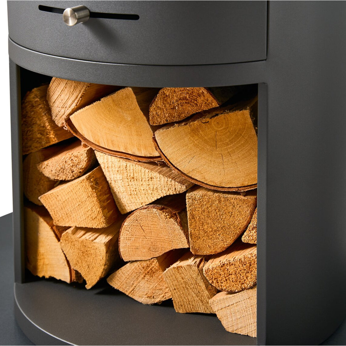 Close-up of a dark gray wood-burning stove or fireplace insert filled with stacked firewood logs, shown against a white background.