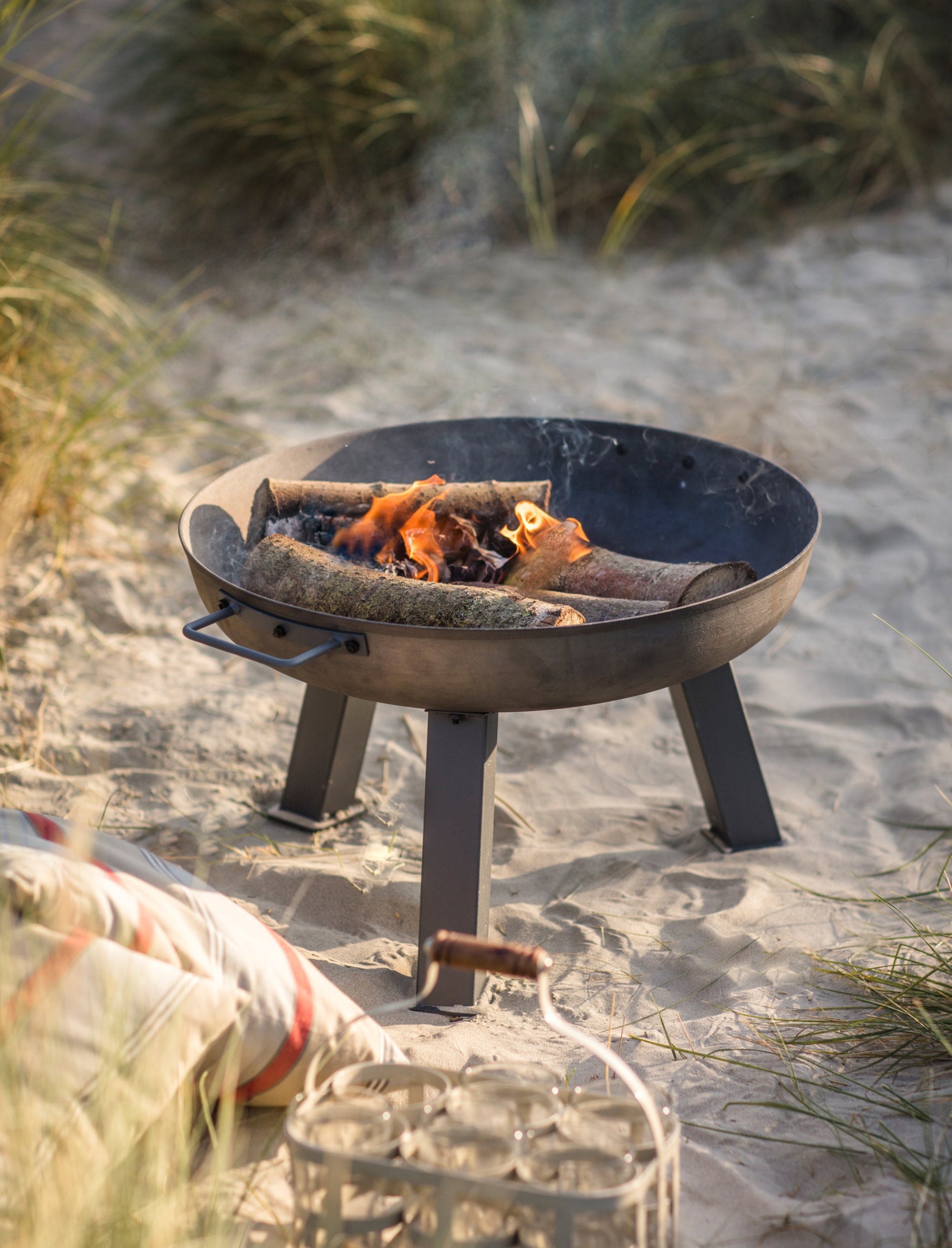 Fire pit on a sandy beach with grasses in the background