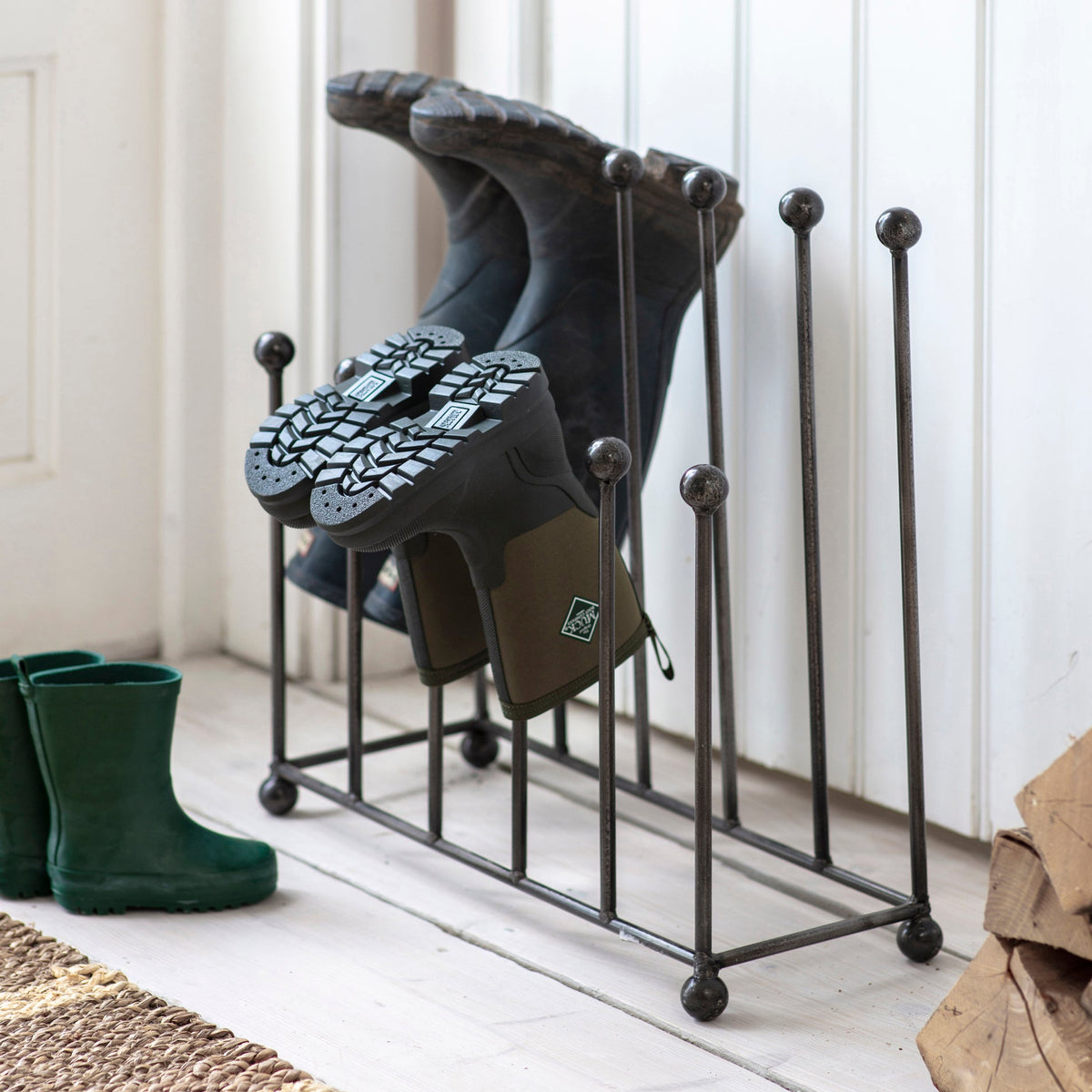 Boot rack holding rain boots on a wooden floor with a white wall background