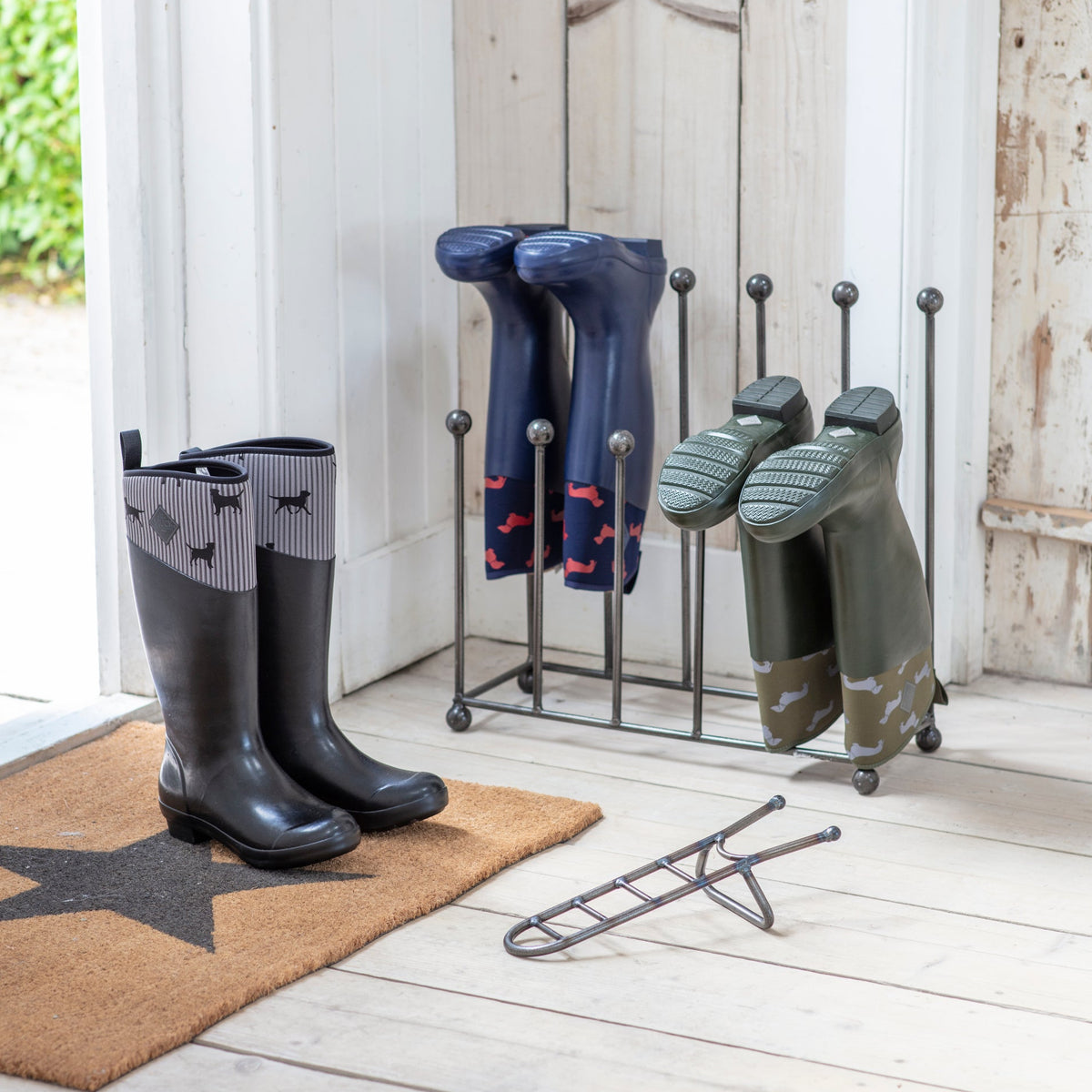 Welly boots on a stand with a doormat featuring a star design.
